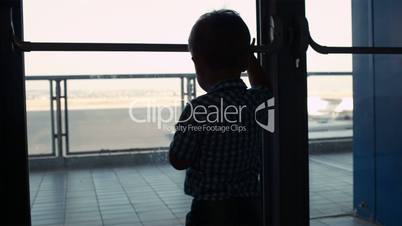 Young boy looking through window in the airport