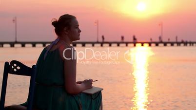 young woman writing in her diary by the seashore