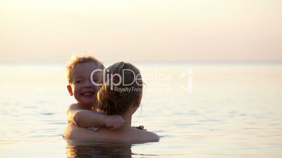 loving mother hugging with her son in the sea