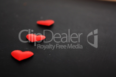 drei rote Herzen liegend auf schwarzem Hintergrund