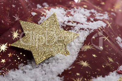 goldener Weihnachtsstern auf Kunstschnee mit Dekoration