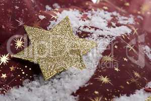 goldener Weihnachtsstern auf Kunstschnee mit Dekoration
