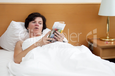 woman is lying in bed reading