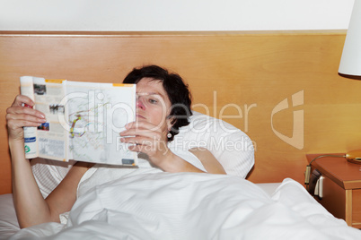 woman is lying in bed reading