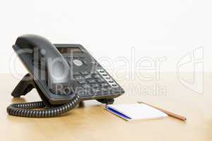 phone on desk with notepad on wooden desk