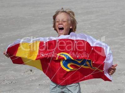 Kind spielt mit Drachen am strand