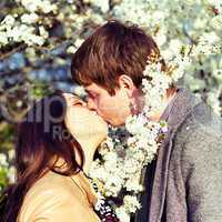 spring outdoor portrait of a young couple kissing