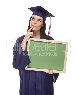 thinking female graduate in cap and gown holding blank chalkboar