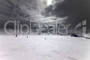 ski slope, skiers and sky with storm clouds