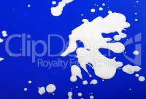 blots from milk on blue background
