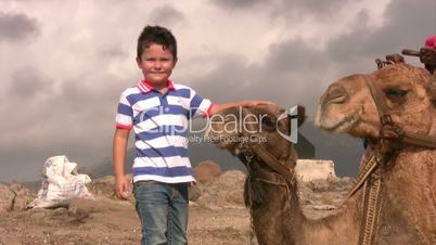 Child touching a camel and smiling at the camera