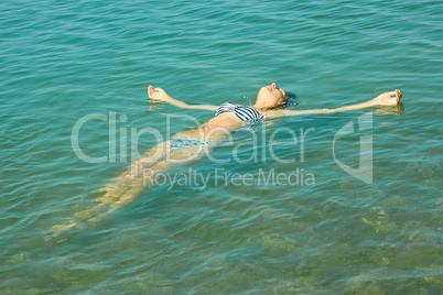 teen girl lying on the sea water surface