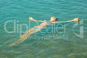 teen girl lying on the sea water surface