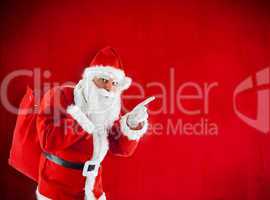 Santa Claus with sack pointing in blank red