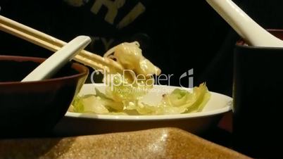 EATING COOKED VEGETABLES WITH A PAIR OF CHOPSTICKS (chopsticks and vegetable)