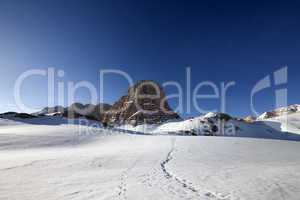 snowy plateau and footpath against rock and blue sky in nice day