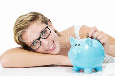 glückliche frau wirft münze in ihr sparschwein