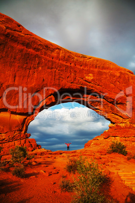 woman staying with raised hands inside an arch