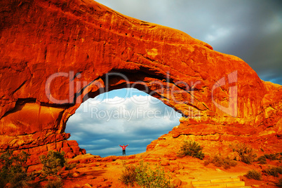 woman staying with raised hands inside an arch