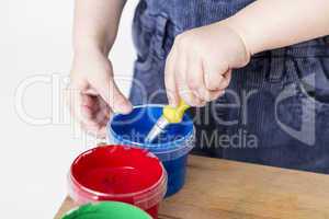 child holding brush in paint tub