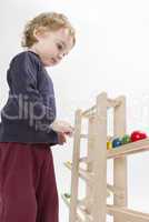 child playing with wooden ball path