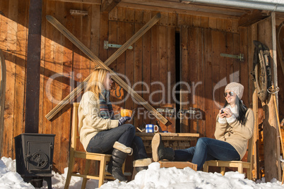 two girlfriends enjoy tea winter snow cottage