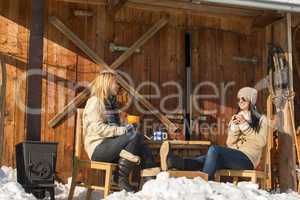 two girlfriends enjoy tea winter snow cottage