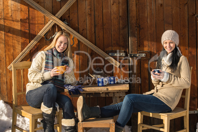 two young women enjoy tea winter cottage