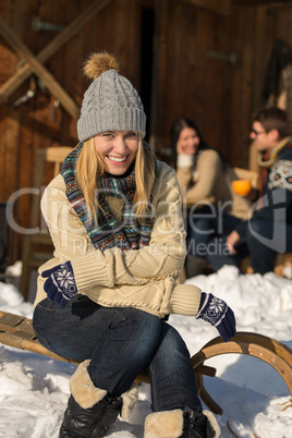 young woman sitting winter snow sledge cottage