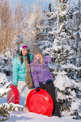 two girlfriends in winter snowy forest bobsleigh