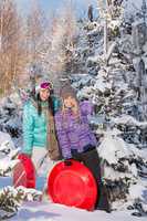 two girlfriends in winter snowy forest bobsleigh
