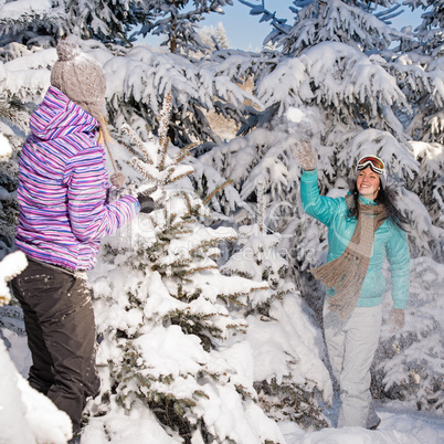 two girlfriends throw snow balls winter forest