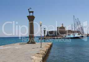 rhodes mandraki harbor with castle and symbolic deer statues, greece