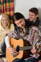 young friends in winter cottage play guitar