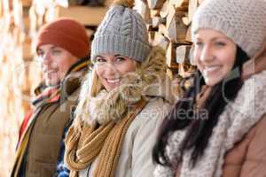 three young people winter fashion wooden logs