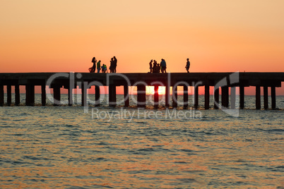 people on the old sea pier during sunset