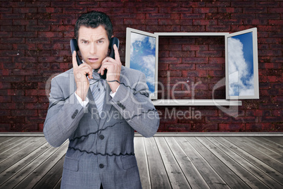 Serious businessman wrapped in cables phoning