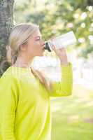 Fit calm blonde drinking from water bottle