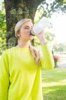 Fit calm blonde drinking from sports bottle