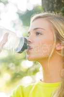 Fit blonde drinking from water bottle