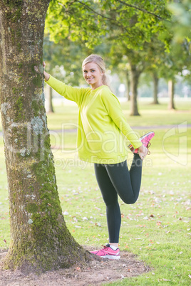 Fit smiling blonde stretching leg