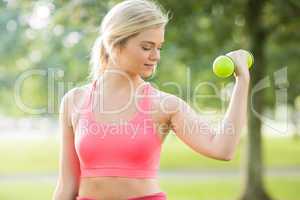 Active smiling blonde lifting dumbbells