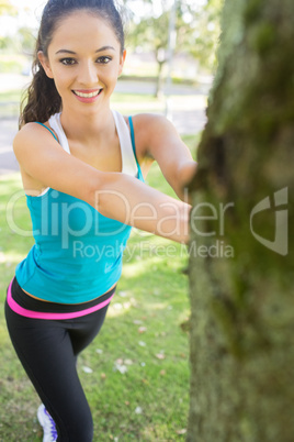 Active smiling brunette stretching her leg