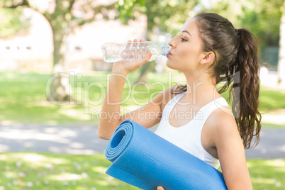 Active peaceful brunette holding exercise mat
