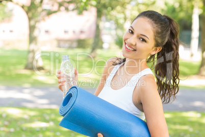 Active smiling brunette holding exercise mat