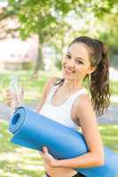 Active cheerful brunette holding exercise mat