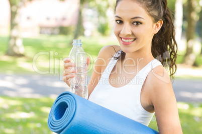 Active content brunette holding exercise mat