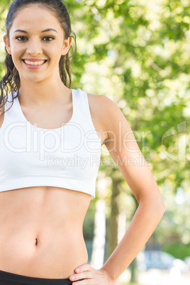 Active smiling brunette standing hands on hips smiling