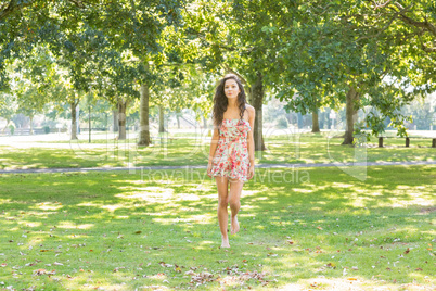 Stylish happy brunette walking on grass
