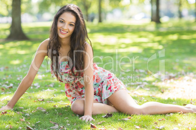Stylish smiling brunette sitting on grass